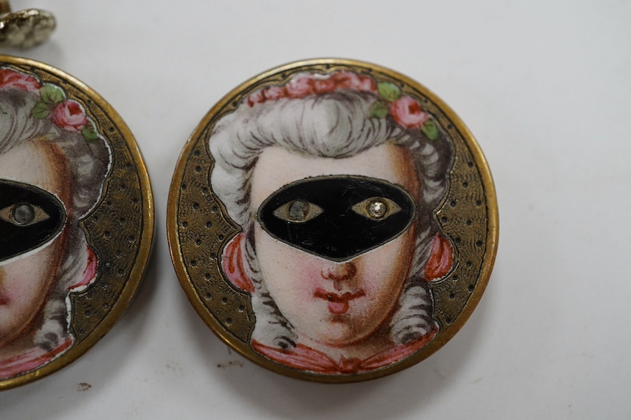 A pair of engraved gilt metal enamel and paste set disc shaped buttons)converted to earrings, one fitting missing), each decorated with a lady wearing a mask, diameter 25mm. Condition - poor to fair